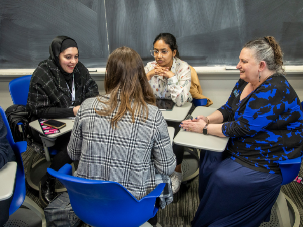 three students gathered around a table with a mentor