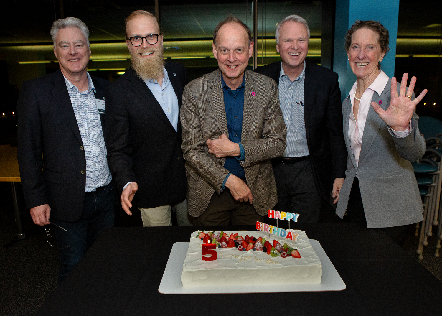 A group of people gather around a 5th birthday cake